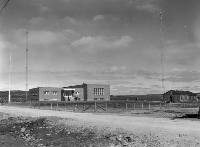 <p>Illustrasjon 1 – Finnmark kringkaster 1950. De store sendemastene er synlig på hver side av bygget. Foto: Henry Hansen/Varanger museum avd. Vadsø museum – Ruija kvenmuseum </p>