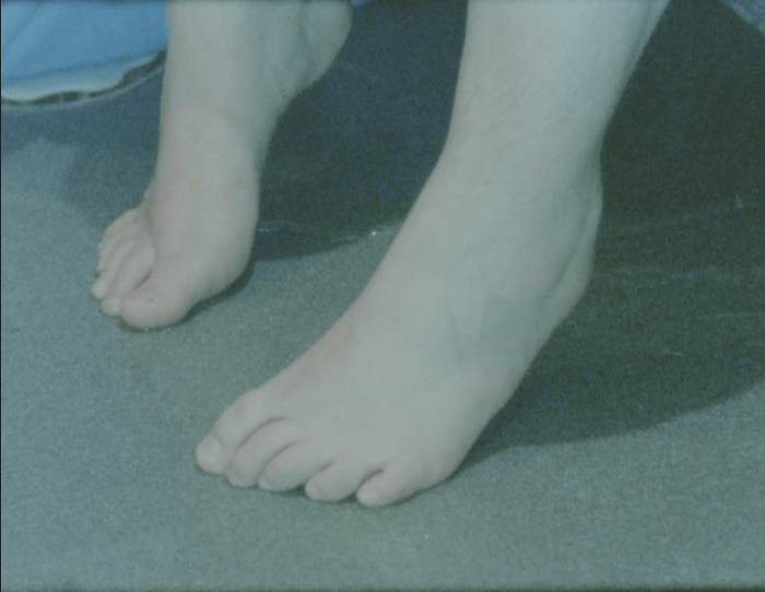 A pair of feet touching the bathroom floor.